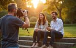 Fotograaf stuurt twee personen aan op stenen treden buiten tijdens gouden uur, met natuurlijke houdingen en zachte achtergrondvervaging
