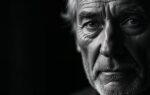 Dramatisch zwart-wit portret van een oudere man met diepe rimpels en expressieve ogen, verlicht met harde zijdelingse belichting die gezichtsstructuur benadrukt